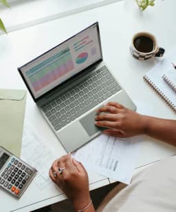 Laptop computer with business charts and calculator on desk